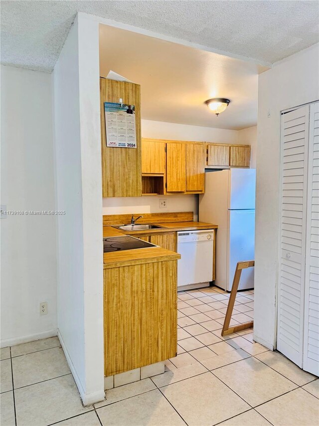 kitchen featuring dishwasher, sink, light tile patterned floors, and refrigerator