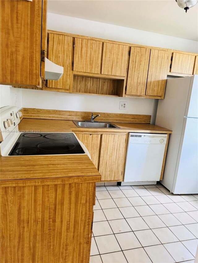 kitchen with sink, light tile patterned floors, white appliances, and range hood