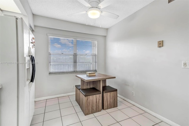 dining room featuring ceiling fan, light tile patterned floors, and a textured ceiling