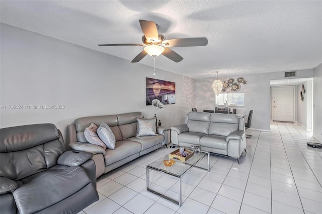 living room featuring ceiling fan, light tile patterned floors, and a textured ceiling