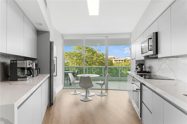 2127 Brickell Ave Unit 705, Miami, FL 33129 - kitchen featuring stainless steel microwave, black electric cooktop, modern cabinets, tasteful backsplash, and light wood finished floors