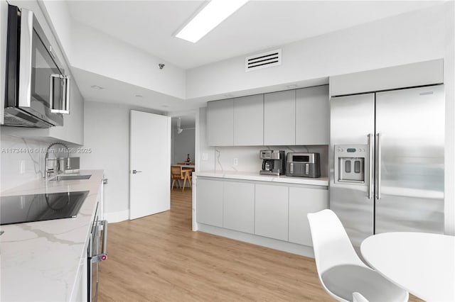 2127 Brickell Ave Unit 705, Miami, FL 33129 - kitchen with stainless steel appliances, light wood-style flooring, modern cabinets, and light stone counters
