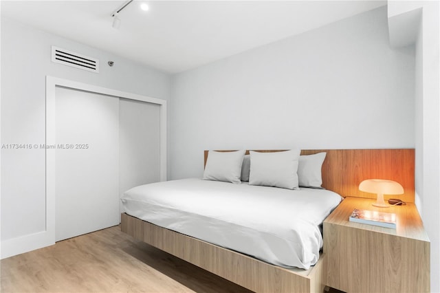 2127 Brickell Ave Unit 705, Miami, FL 33129 - bedroom with rail lighting, light wood-style flooring, and a closet