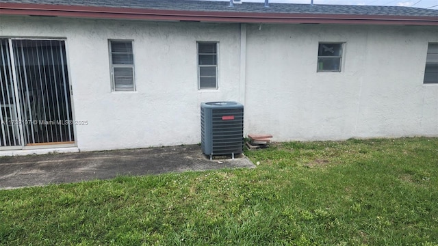 view of side of home featuring cooling unit and a lawn