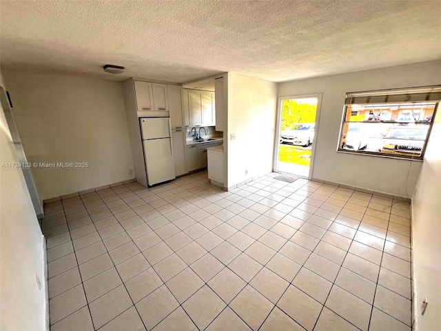 empty room with sink, light tile patterned floors, and a textured ceiling