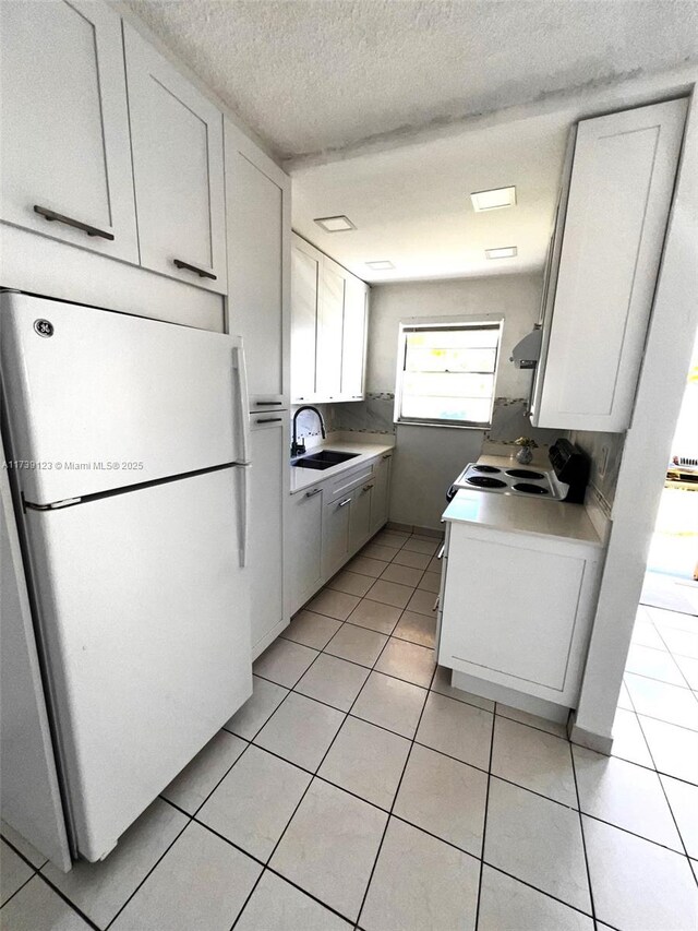 kitchen featuring extractor fan, white cabinetry, sink, white fridge, and light tile patterned floors