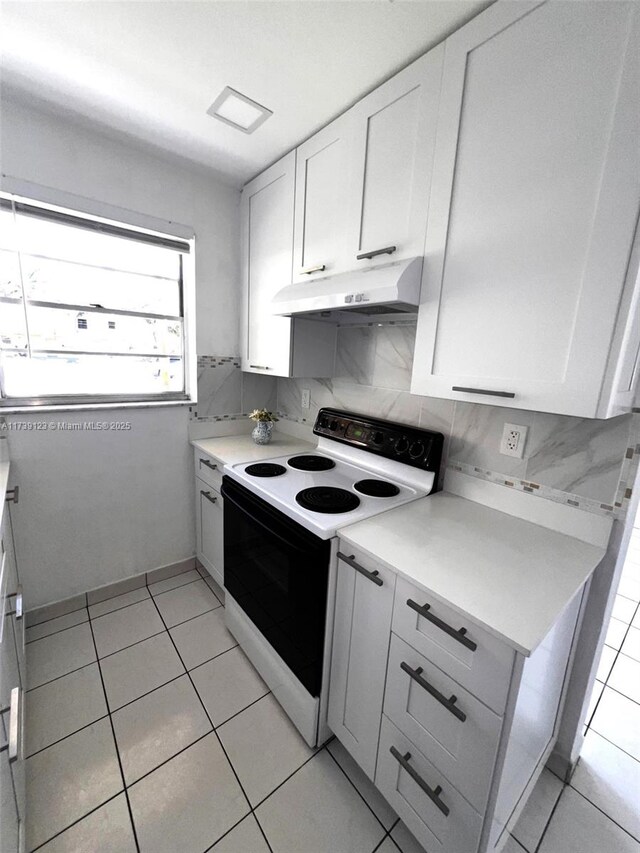 kitchen with light tile patterned floors, white cabinets, backsplash, and electric stove