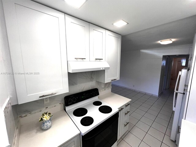 kitchen featuring light tile patterned flooring, white cabinetry, range with electric stovetop, white fridge, and decorative backsplash