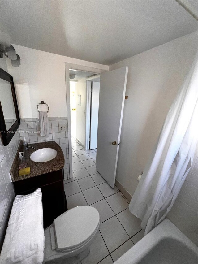 full bathroom featuring tile walls, vanity, toilet, tile patterned floors, and shower / bath combo with shower curtain