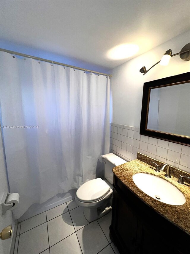 bathroom featuring tile walls, vanity, walk in shower, toilet, and tile patterned floors