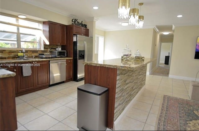 kitchen with hanging light fixtures, ornamental molding, a kitchen island, stainless steel appliances, and decorative backsplash