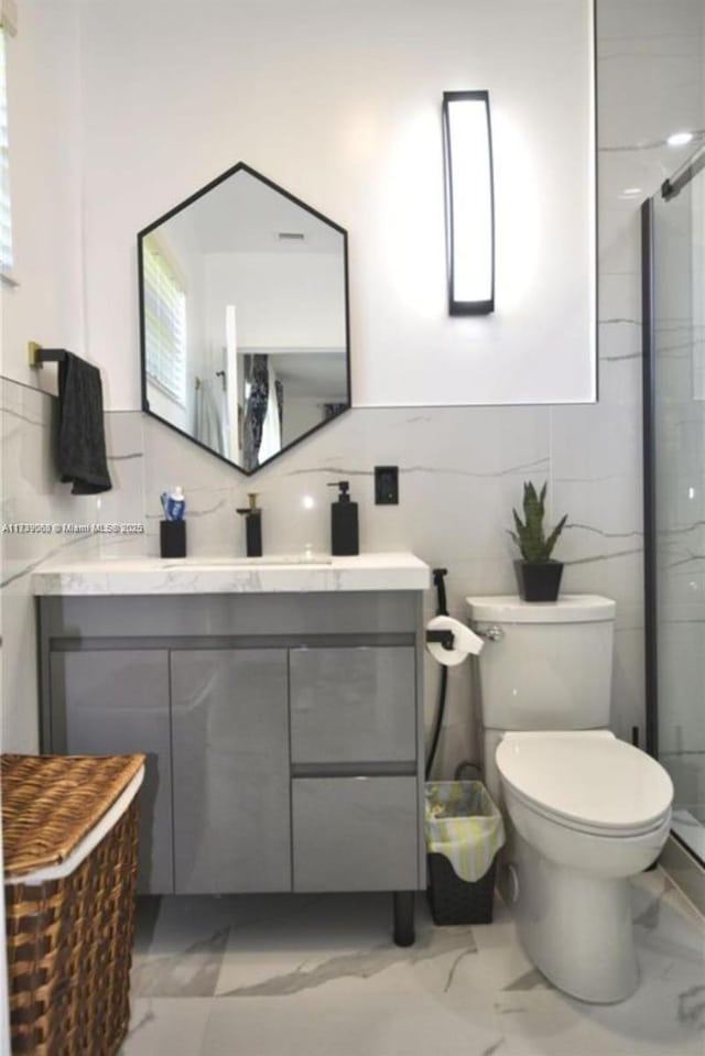 bathroom with vanity, an enclosed shower, tile walls, and toilet