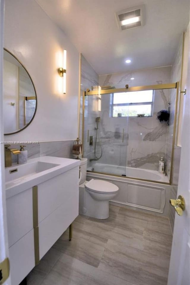 full bathroom with vanity, shower / bath combination with glass door, and toilet