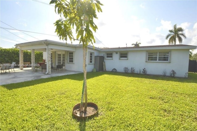 back of house with a patio and a lawn