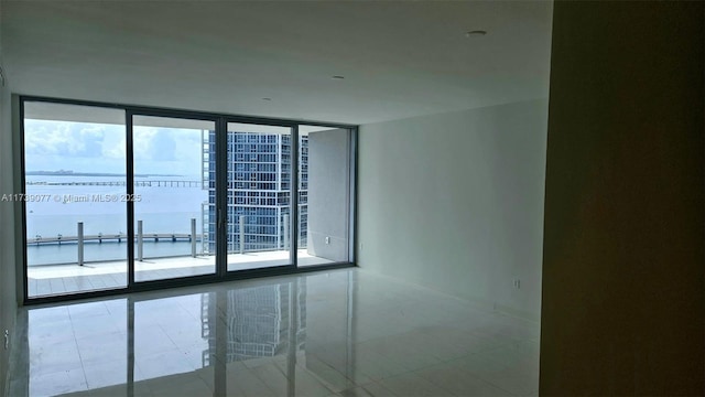 spare room with a water view and a wall of windows