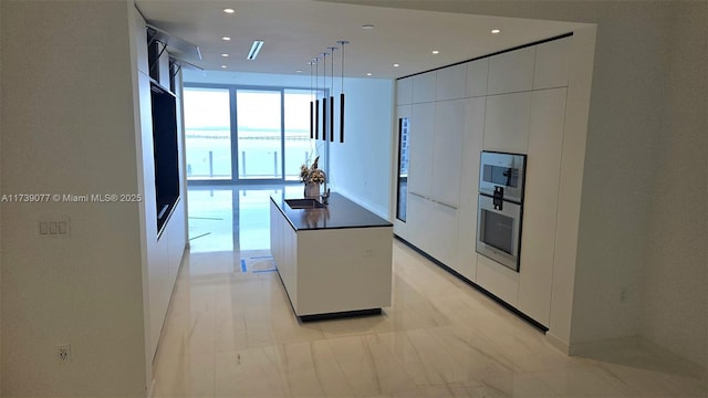 kitchen featuring sink, a center island, pendant lighting, oven, and white cabinets