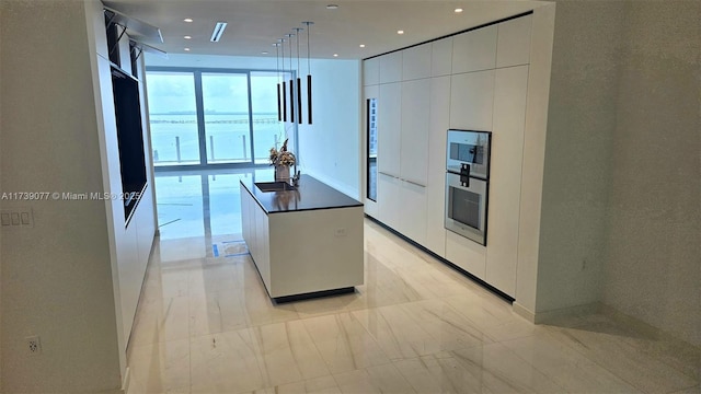 kitchen with hanging light fixtures, stainless steel oven, white cabinets, and a center island