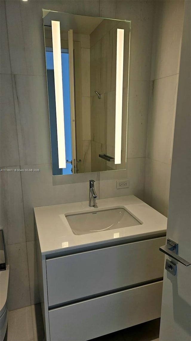 bathroom featuring vanity, toilet, and tile walls