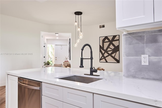 kitchen with pendant lighting, sink, white cabinets, stainless steel dishwasher, and light stone countertops