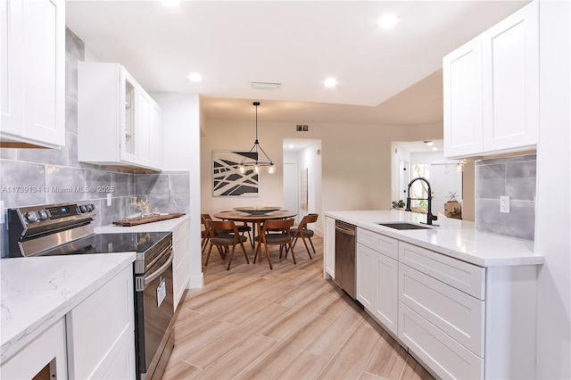 kitchen featuring sink, white cabinetry, pendant lighting, stainless steel appliances, and backsplash