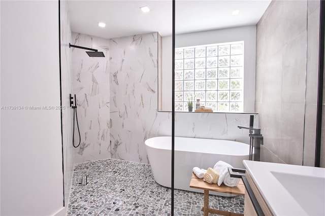 bathroom with independent shower and bath, vanity, and tile walls