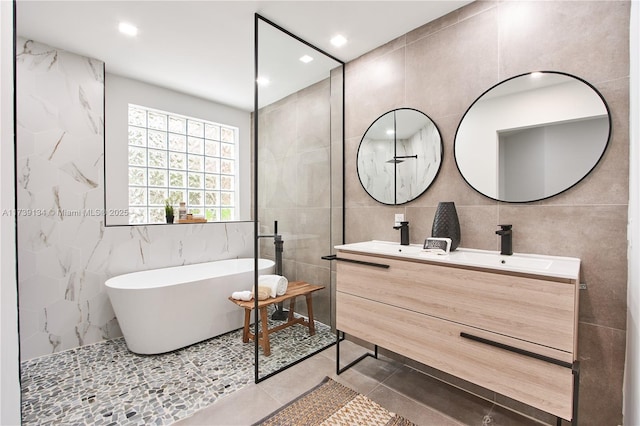 bathroom featuring vanity, a bath, tile patterned flooring, and tile walls