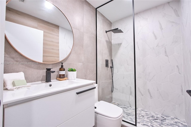 bathroom with vanity, toilet, tile walls, and tiled shower