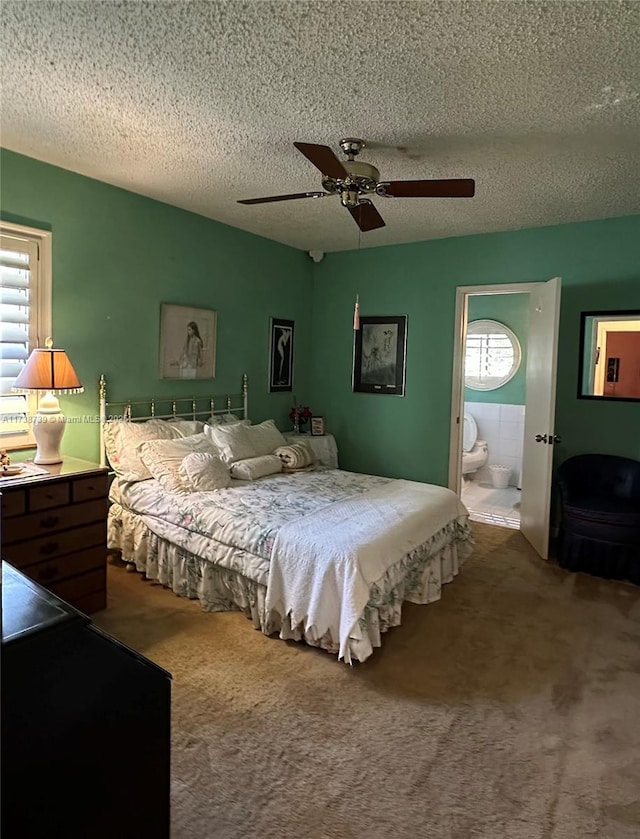 carpeted bedroom featuring a textured ceiling, ceiling fan, and ensuite bath