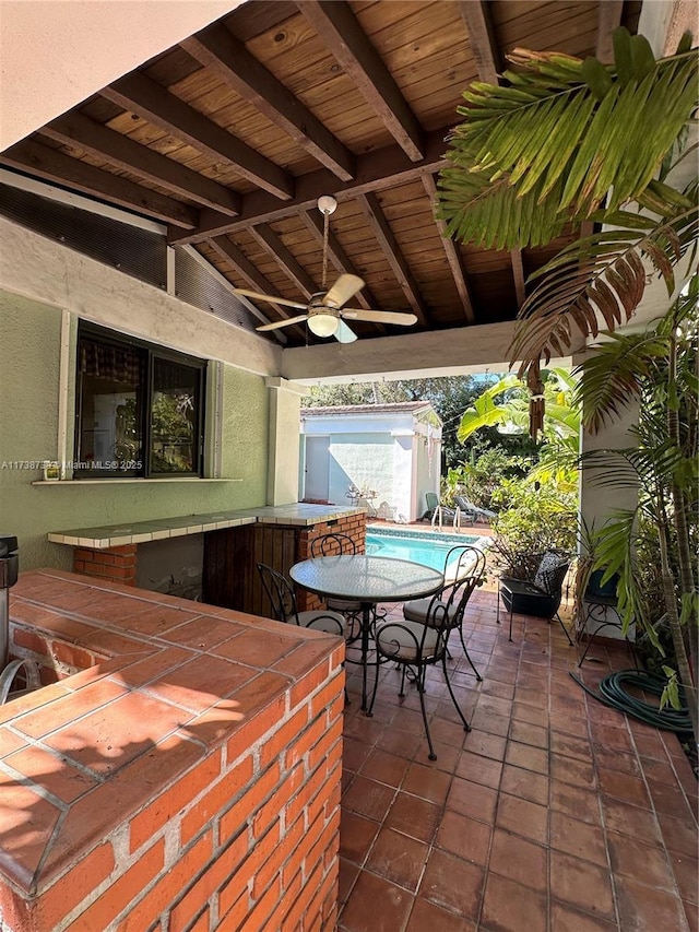 view of patio with ceiling fan, a shed, a bar, and an outdoor structure