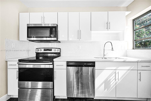 kitchen featuring white cabinetry, sink, backsplash, light stone counters, and stainless steel appliances