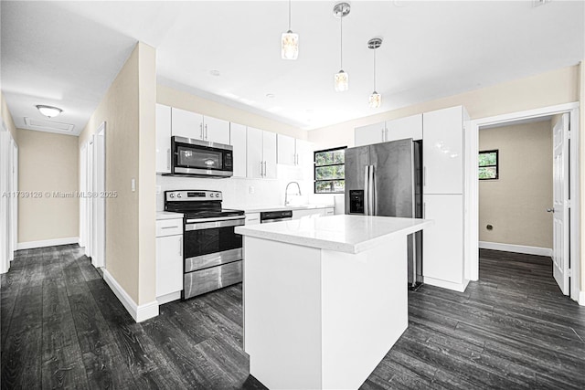 kitchen featuring stainless steel appliances, a kitchen island, hanging light fixtures, and white cabinets