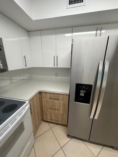 kitchen featuring light tile patterned flooring, white cabinetry, visible vents, light countertops, and stainless steel fridge with ice dispenser