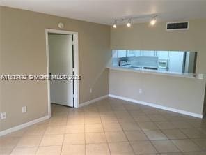 tiled empty room with rail lighting, baseboards, and visible vents