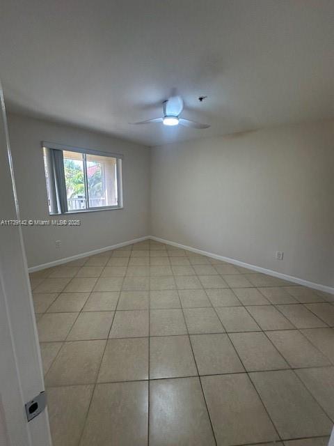 unfurnished room with ceiling fan, baseboards, and light tile patterned floors