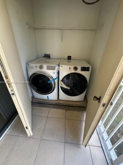 clothes washing area with laundry area, washer and clothes dryer, and light tile patterned flooring