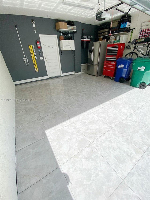 garage with a garage door opener and stainless steel refrigerator with ice dispenser