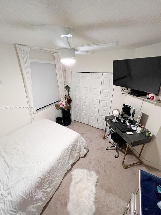 carpeted bedroom featuring ceiling fan, a closet, and a textured ceiling