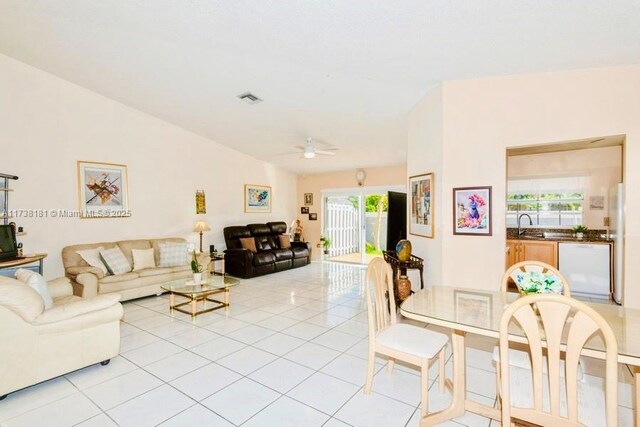 living room with ceiling fan, sink, vaulted ceiling, and light tile patterned floors