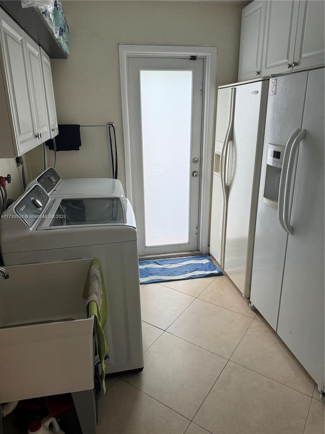 clothes washing area with cabinets, washer and clothes dryer, and light tile patterned floors