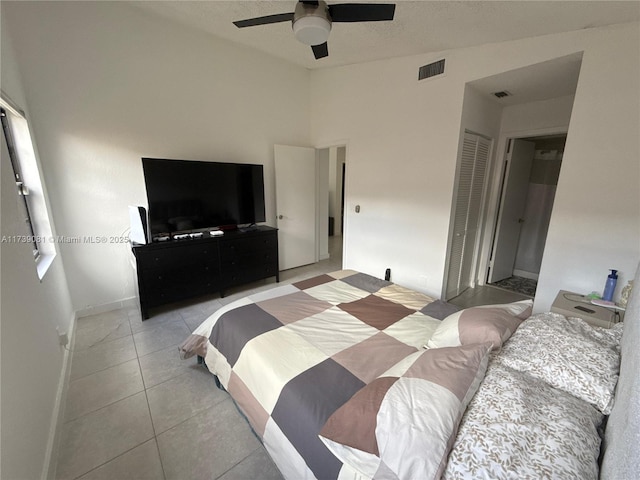 tiled bedroom with ceiling fan, vaulted ceiling, a closet, and a textured ceiling