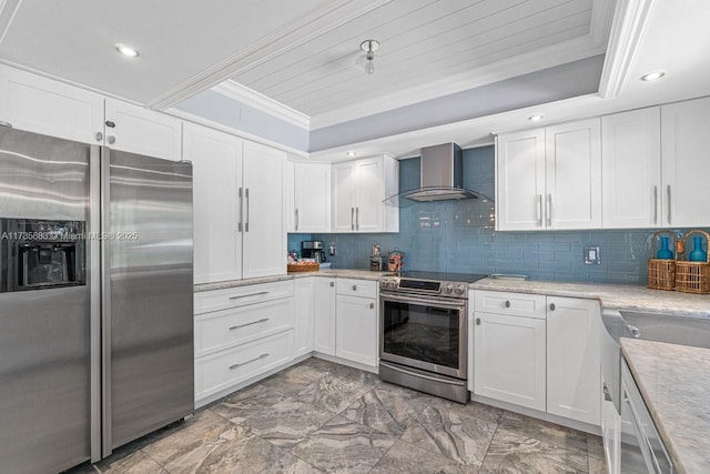 kitchen featuring crown molding, stainless steel appliances, a tray ceiling, white cabinets, and wall chimney exhaust hood