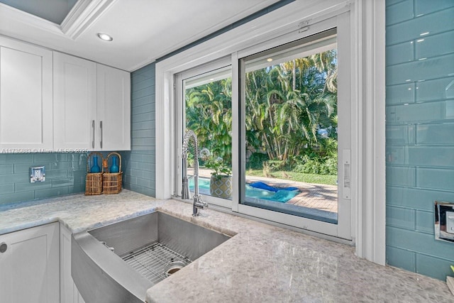 kitchen featuring decorative backsplash, light stone countertops, and white cabinets