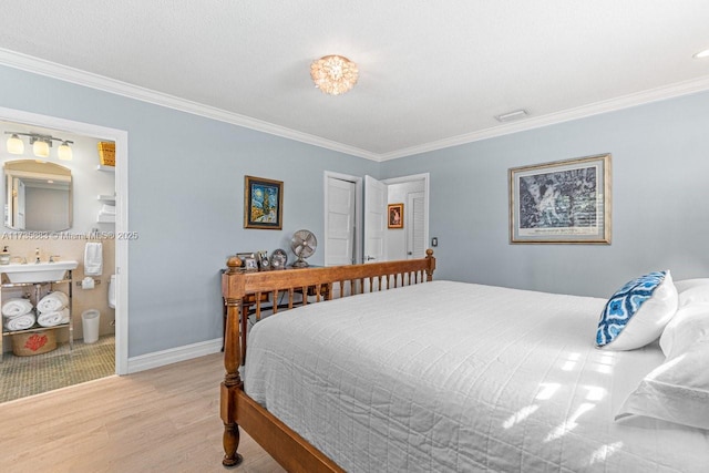 bedroom featuring ornamental molding, sink, light hardwood / wood-style floors, and ensuite bath