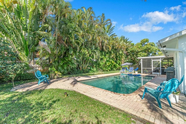 view of swimming pool featuring a patio, a sunroom, and a lawn