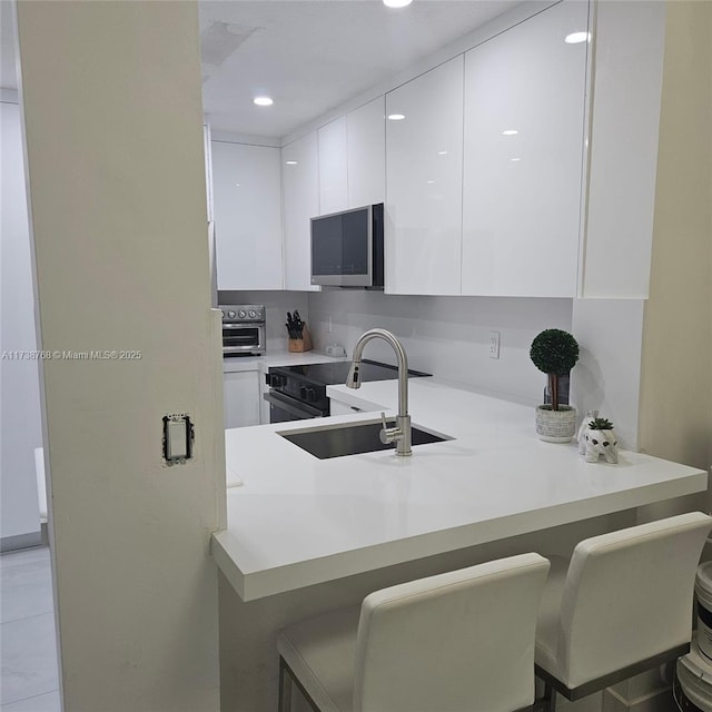 kitchen with sink, white cabinetry, backsplash, a kitchen breakfast bar, and kitchen peninsula