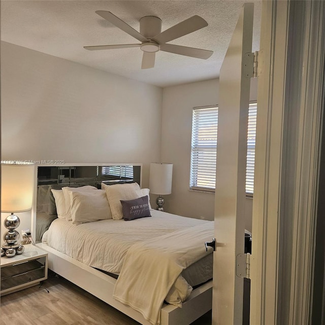 bedroom featuring ceiling fan, hardwood / wood-style flooring, and a textured ceiling