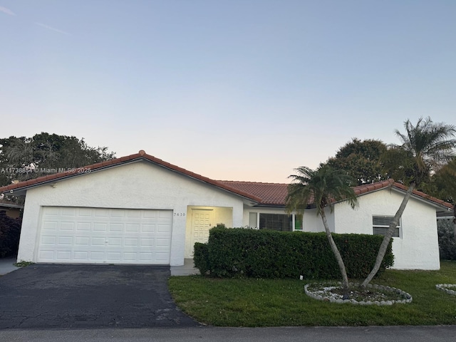 ranch-style house with a garage and a yard