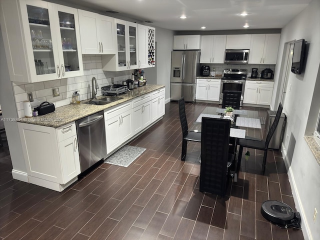 kitchen featuring stainless steel appliances, light stone countertops, sink, and white cabinets