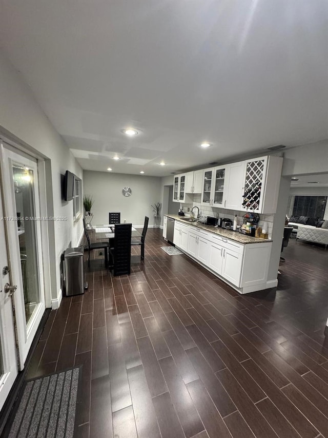 kitchen featuring sink, dark wood-type flooring, dishwasher, white cabinetry, and light stone countertops