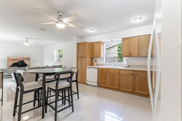 kitchen featuring white appliances, light countertops, brown cabinetry, ceiling fan, and a sink
